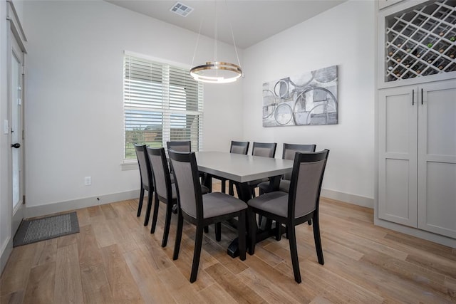 dining room with baseboards, visible vents, and light wood finished floors