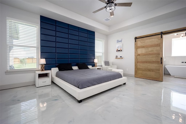 bedroom with a barn door, multiple windows, a raised ceiling, and baseboards