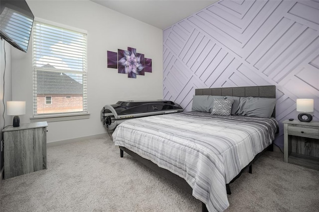 carpeted bedroom featuring an accent wall and baseboards