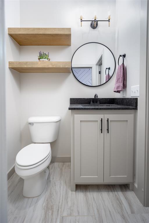 bathroom featuring baseboards, vanity, and toilet