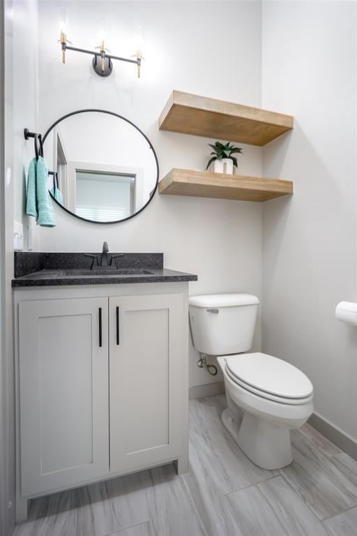 bathroom featuring vanity, toilet, and baseboards