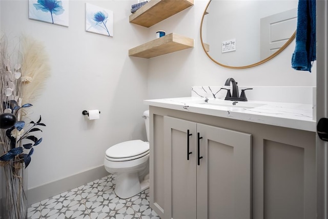 half bathroom with baseboards, vanity, toilet, and tile patterned floors