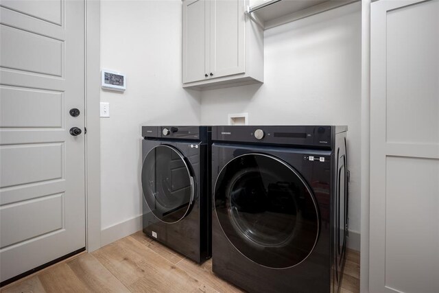 laundry room with light wood-type flooring, washer and dryer, cabinet space, and baseboards