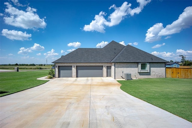 view of front of house featuring an attached garage, central AC, fence, concrete driveway, and a front yard