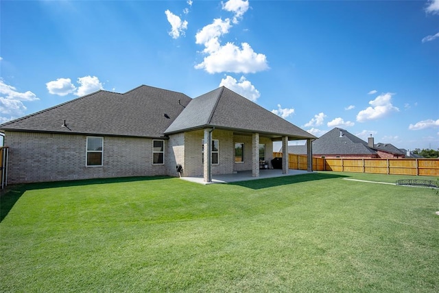 back of property featuring a yard, brick siding, a patio, and a fenced backyard