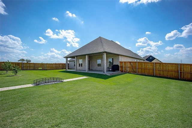 back of house with a patio area, a fenced backyard, brick siding, and a yard