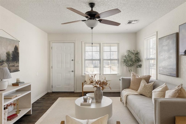 living area featuring a textured ceiling, a wealth of natural light, wood finished floors, and visible vents