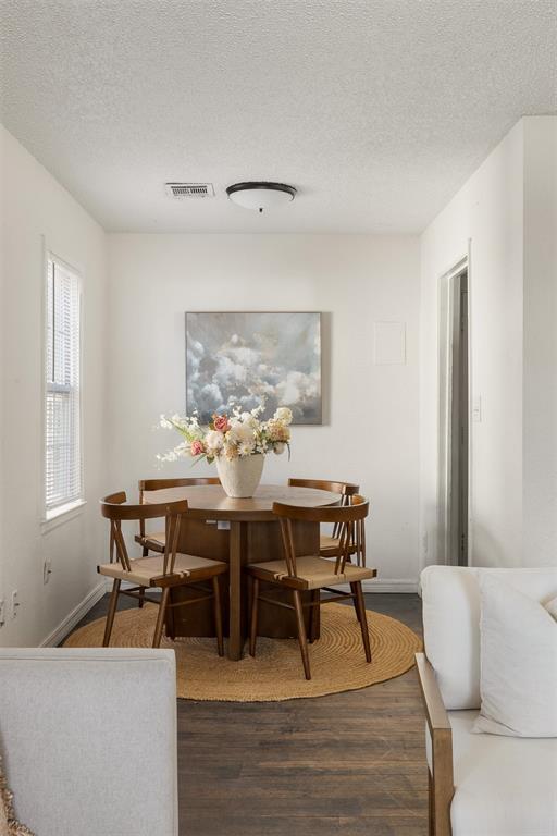 dining room with visible vents, dark wood finished floors, a textured ceiling, and baseboards