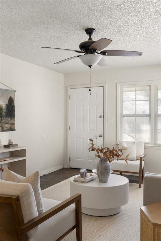 living room with a ceiling fan, a textured ceiling, and baseboards