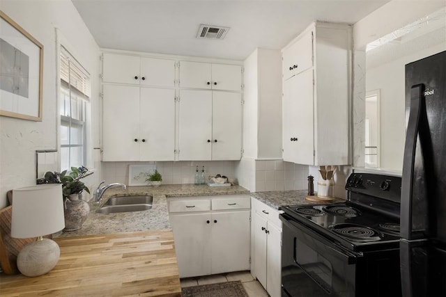 kitchen with decorative backsplash, white cabinetry, a sink, and black appliances