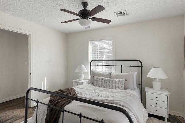 bedroom with visible vents, ceiling fan, a textured ceiling, wood finished floors, and baseboards