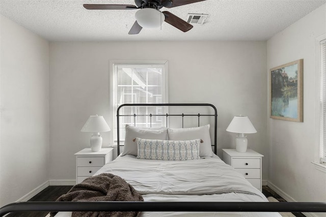 bedroom featuring ceiling fan, dark wood finished floors, visible vents, and baseboards