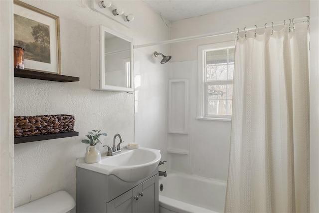 full bathroom featuring shower / bath combination with curtain, a textured wall, vanity, and toilet