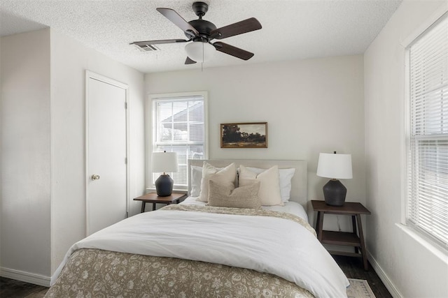 bedroom featuring a textured ceiling, wood finished floors, a ceiling fan, visible vents, and baseboards