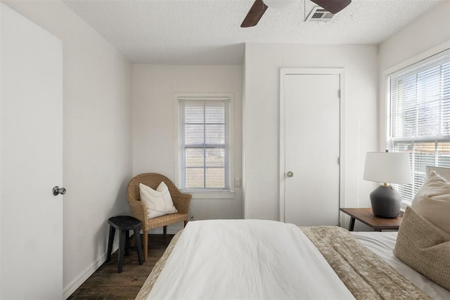 bedroom featuring baseboards, visible vents, ceiling fan, wood finished floors, and a textured ceiling