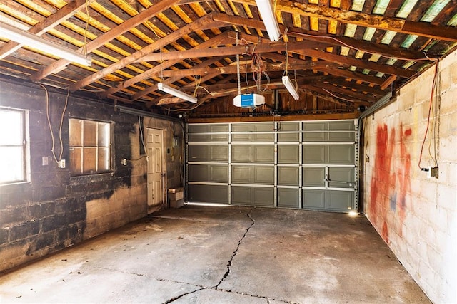 garage featuring concrete block wall and a garage door opener