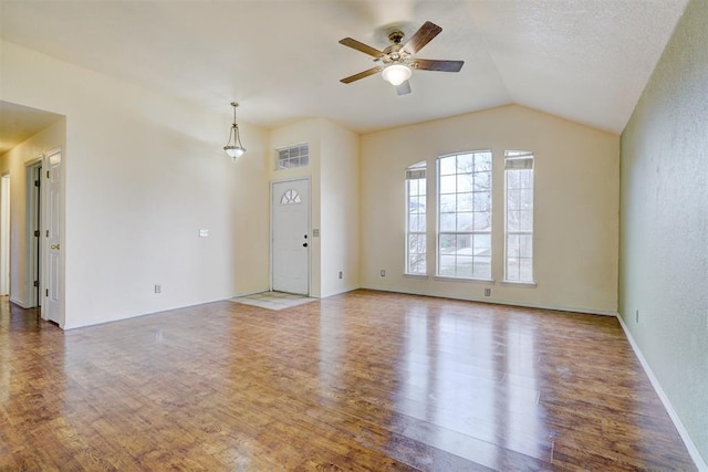 unfurnished living room with a ceiling fan, vaulted ceiling, wood finished floors, and baseboards