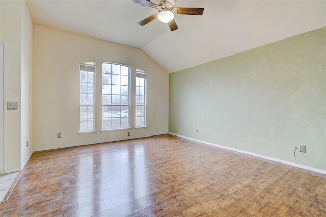 empty room featuring baseboards, light wood-style flooring, a ceiling fan, and vaulted ceiling