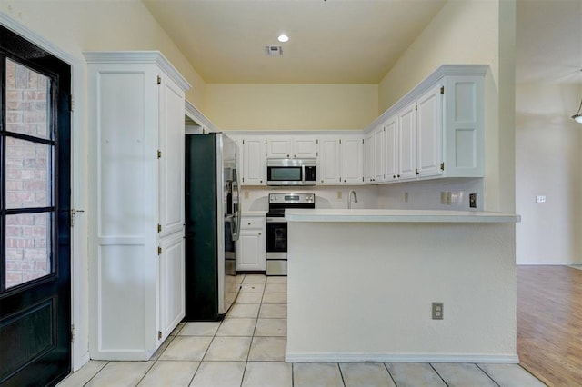 kitchen with light countertops, white cabinets, light tile patterned flooring, and appliances with stainless steel finishes