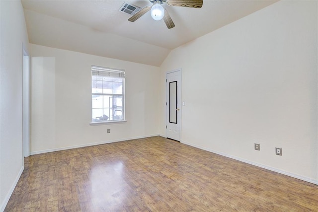 empty room featuring visible vents, wood finished floors, baseboards, ceiling fan, and vaulted ceiling