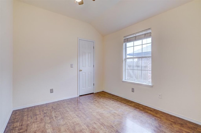 empty room featuring lofted ceiling, wood finished floors, baseboards, and ceiling fan