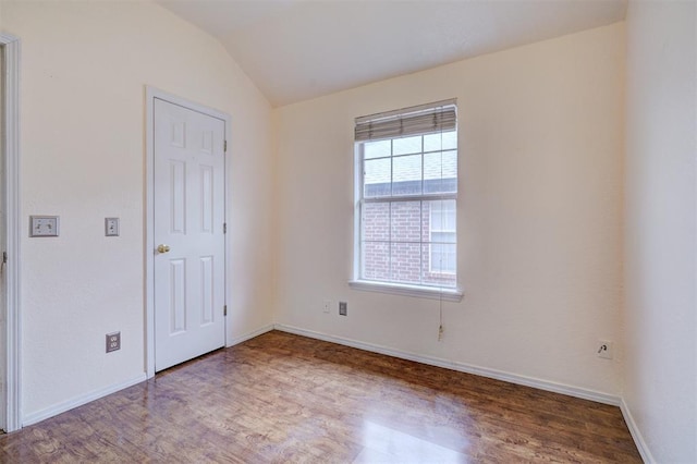 unfurnished room with baseboards, lofted ceiling, and wood finished floors