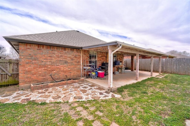 back of property with a patio, a fenced backyard, brick siding, and a lawn