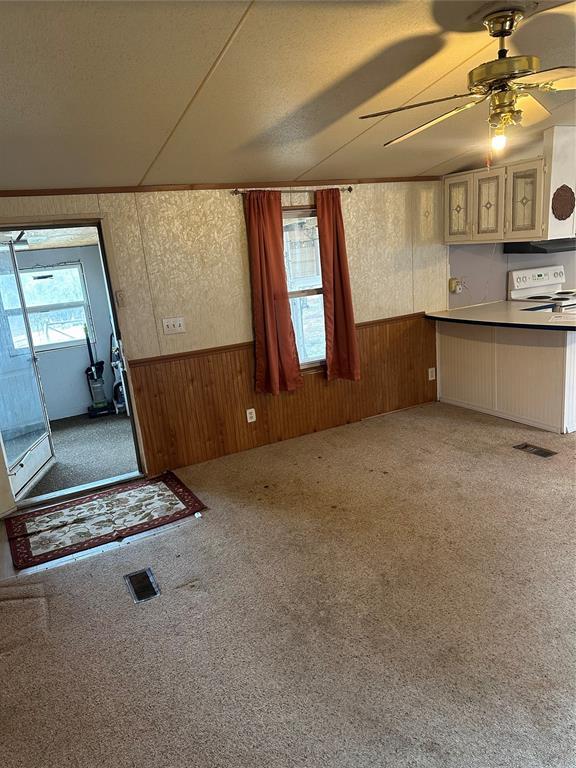 kitchen with white range with electric stovetop, wood walls, wainscoting, and visible vents