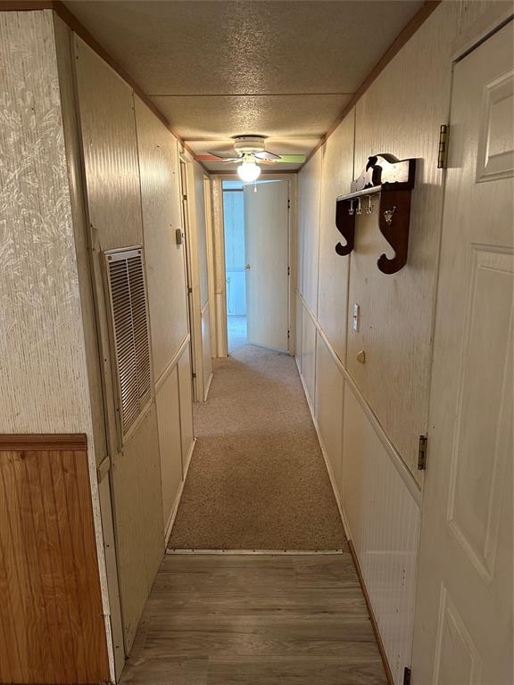 hall featuring light wood-style flooring, visible vents, and a textured ceiling