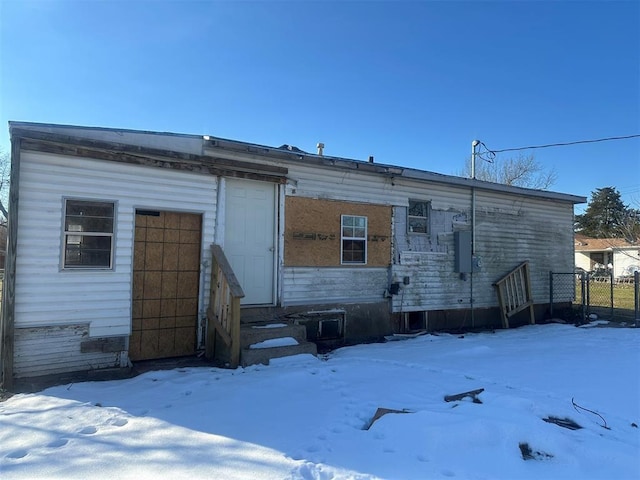 snow covered rear of property with fence