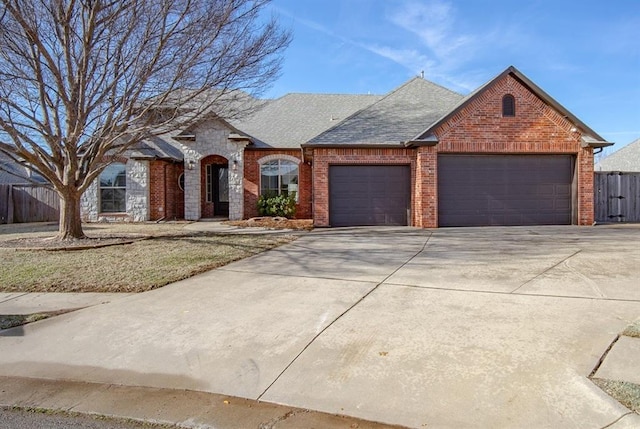 view of front of house with a garage, fence, concrete driveway, and brick siding