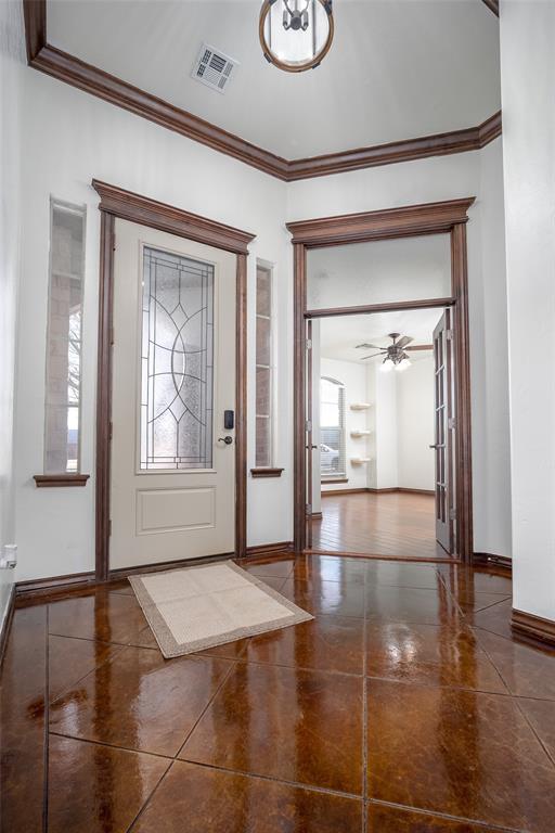 entryway featuring a ceiling fan, baseboards, visible vents, and crown molding