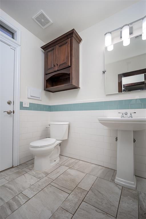 3520 SW 123rd Pl, Oklahoma City, OK 73170 - half bath featuring toilet, visible vents, tile walls, marble finish floor, and wainscoting