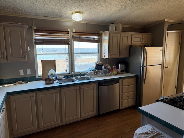 kitchen with dark wood-style floors, appliances with stainless steel finishes, ornamental molding, light countertops, and a sink