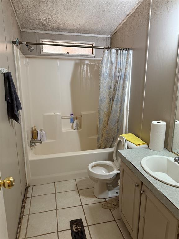 bathroom featuring toilet, shower / bath combination with curtain, tile patterned flooring, and a textured ceiling