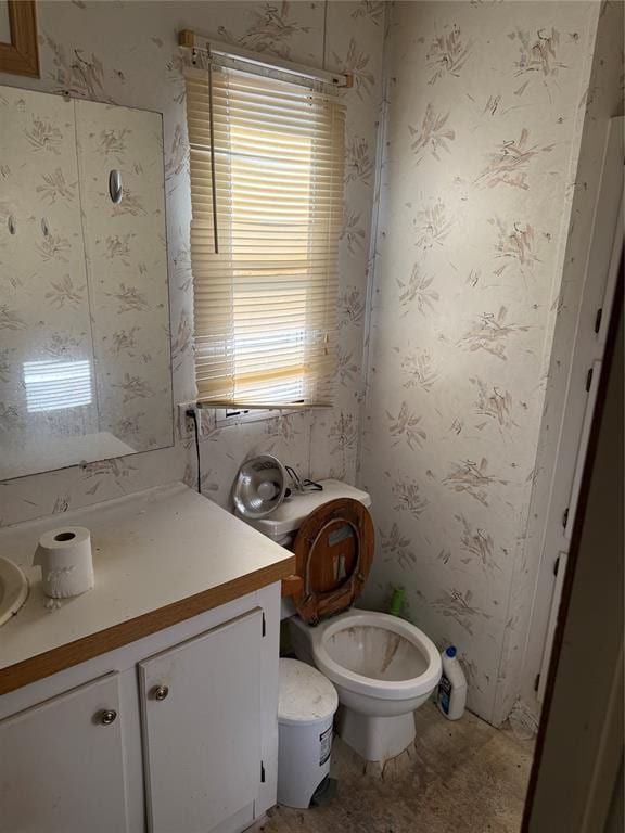 bathroom with toilet, wallpapered walls, and vanity