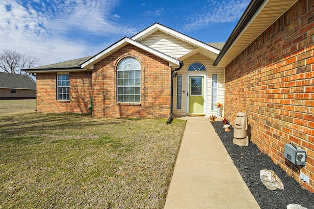 entrance to property with a yard and brick siding