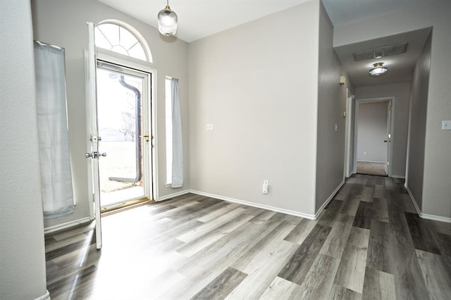 foyer entrance with baseboards, visible vents, and wood finished floors