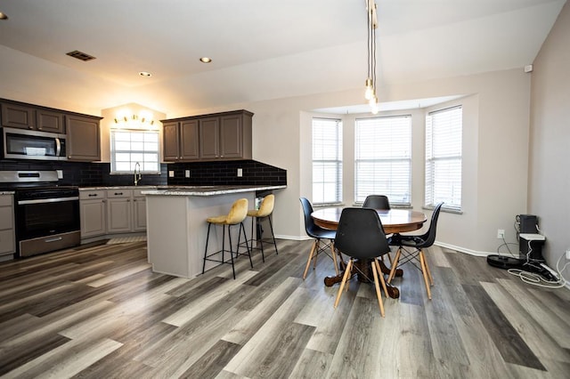 kitchen with tasteful backsplash, visible vents, dark wood finished floors, lofted ceiling, and appliances with stainless steel finishes