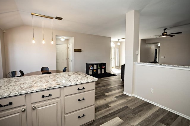 kitchen with light stone counters, pendant lighting, visible vents, dark wood-type flooring, and ceiling fan