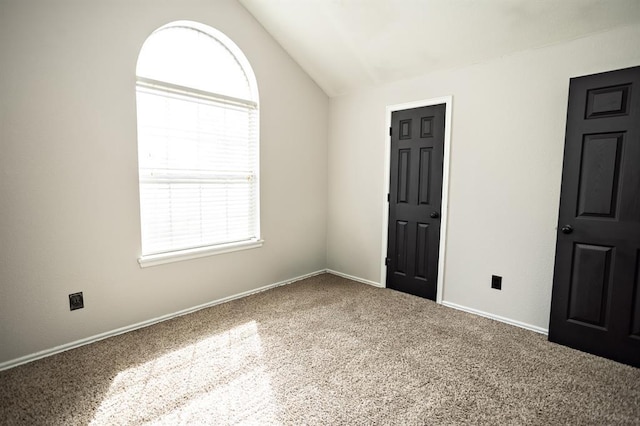 carpeted spare room with vaulted ceiling and baseboards