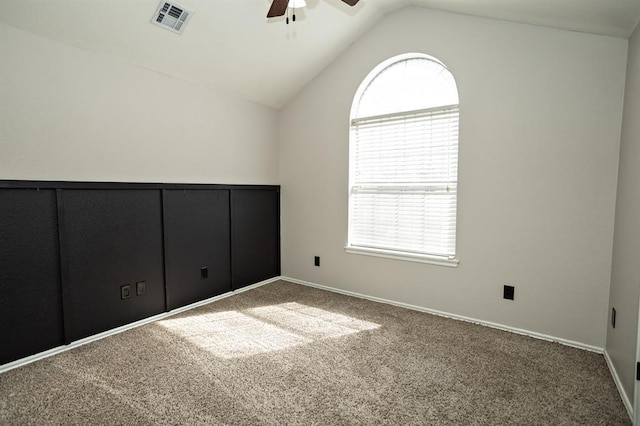 carpeted empty room featuring visible vents, vaulted ceiling, baseboards, and ceiling fan