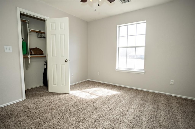 unfurnished bedroom with a closet, visible vents, a spacious closet, carpet flooring, and baseboards