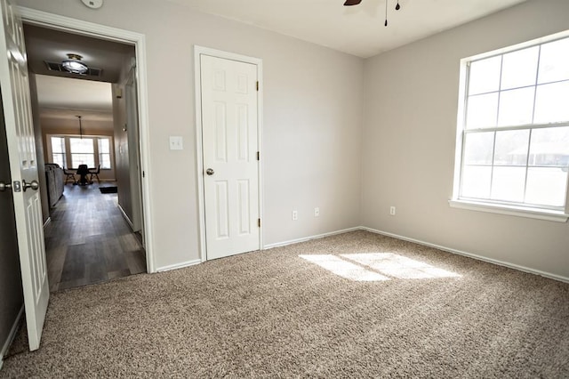 carpeted spare room featuring ceiling fan and baseboards