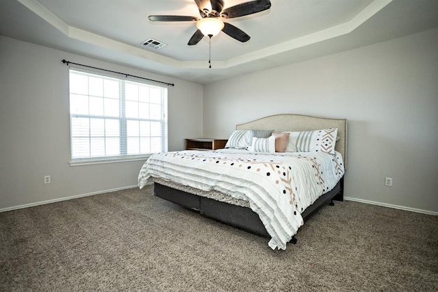 bedroom with a tray ceiling, carpet flooring, visible vents, and baseboards