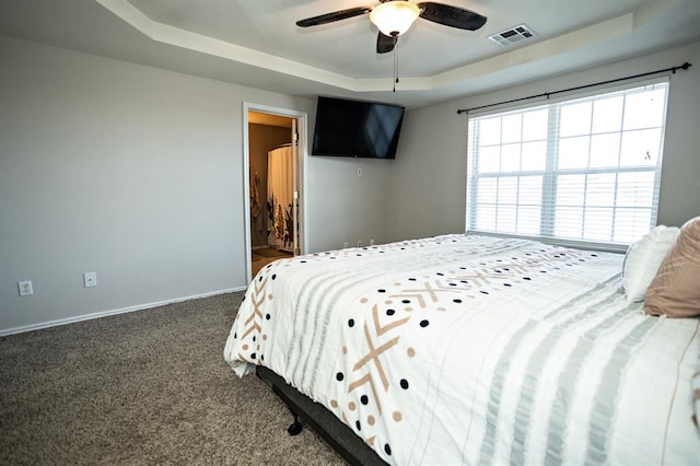 bedroom featuring a tray ceiling, carpet, visible vents, ceiling fan, and baseboards