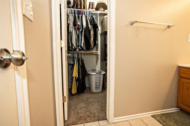 bathroom featuring a walk in closet, vanity, baseboards, and tile patterned floors