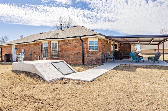 back of property with a patio, brick siding, and a shingled roof