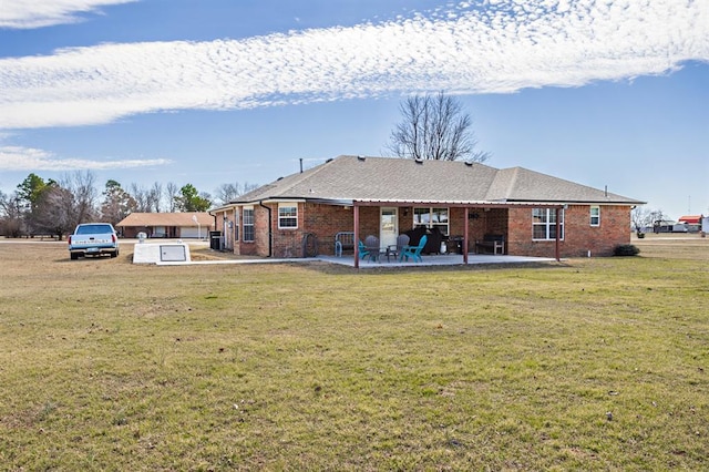 back of property with a yard, a patio area, and brick siding