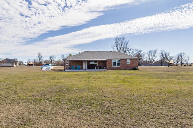 rear view of house with a patio area, a yard, and brick siding